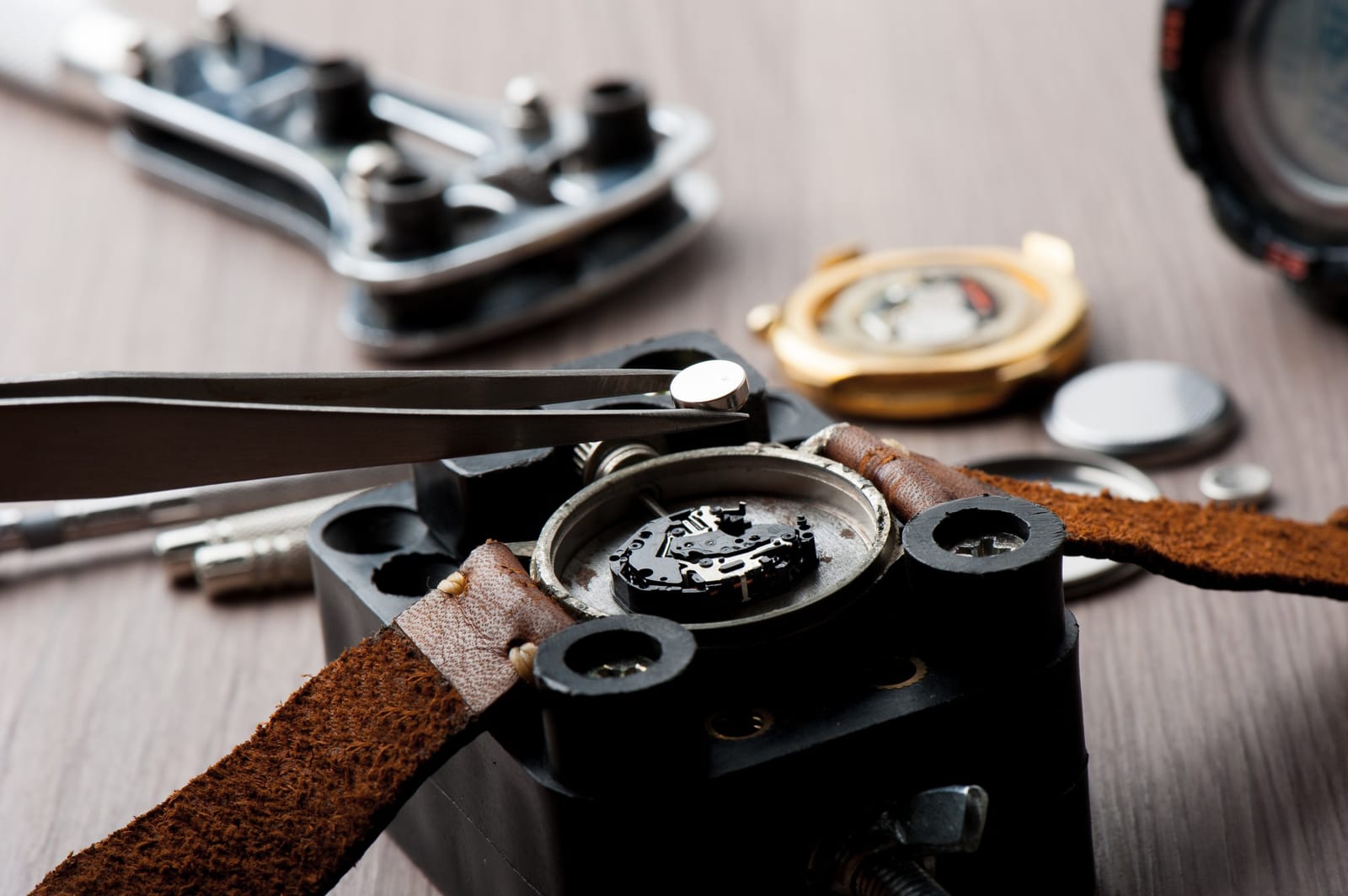 Pinzette che regolano un componente nella cassa aperta di un orologio da polso